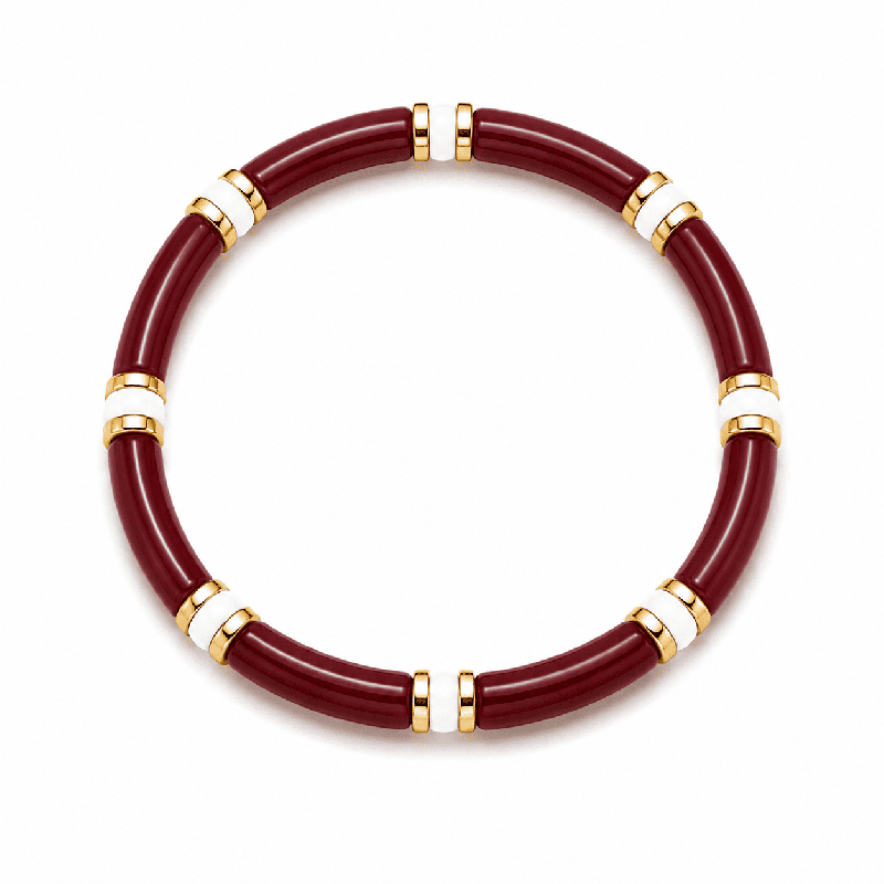 Pulsera elástica de diseño elegante con piezas tubulares y delicados detalles dorados y blancos.
