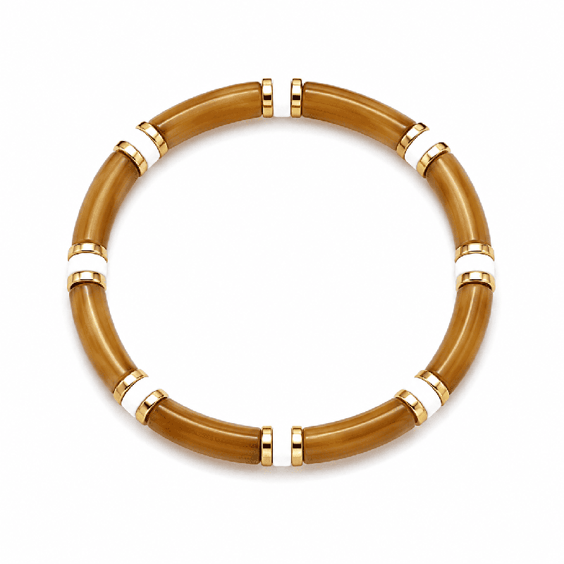 Pulsera elástica de diseño elegante con piezas tubulares y delicados detalles dorados y blancos.
