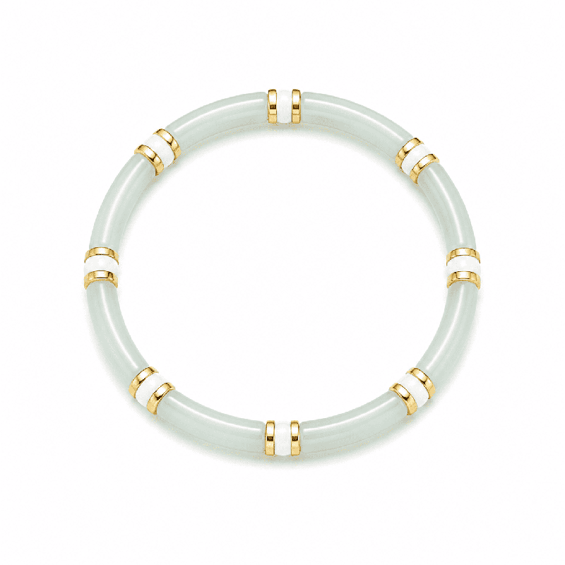 Pulsera elástica de diseño elegante con piezas tubulares y delicados detalles dorados y blancos.