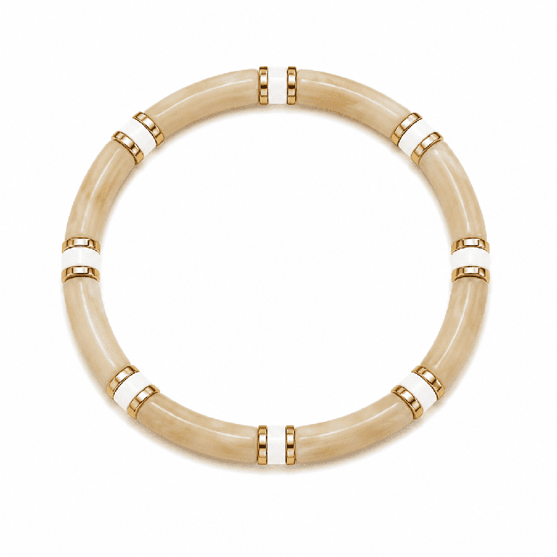 Pulsera elástica de diseño elegante con piezas tubulares y delicados detalles dorados y blancos.